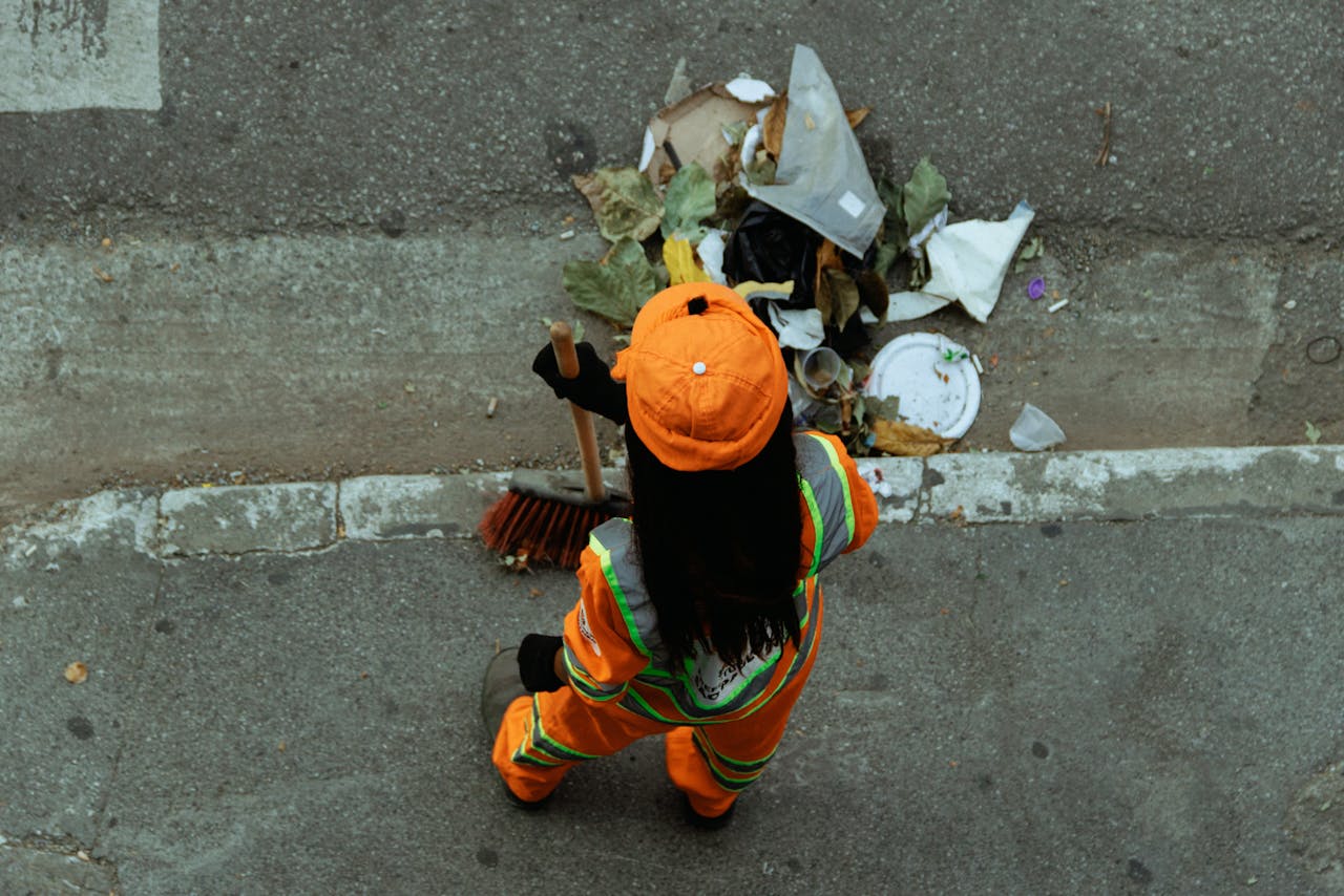 home-hero A street cleaner in an orange uniform sweeps debris from the roadside, ensuring cleanliness.